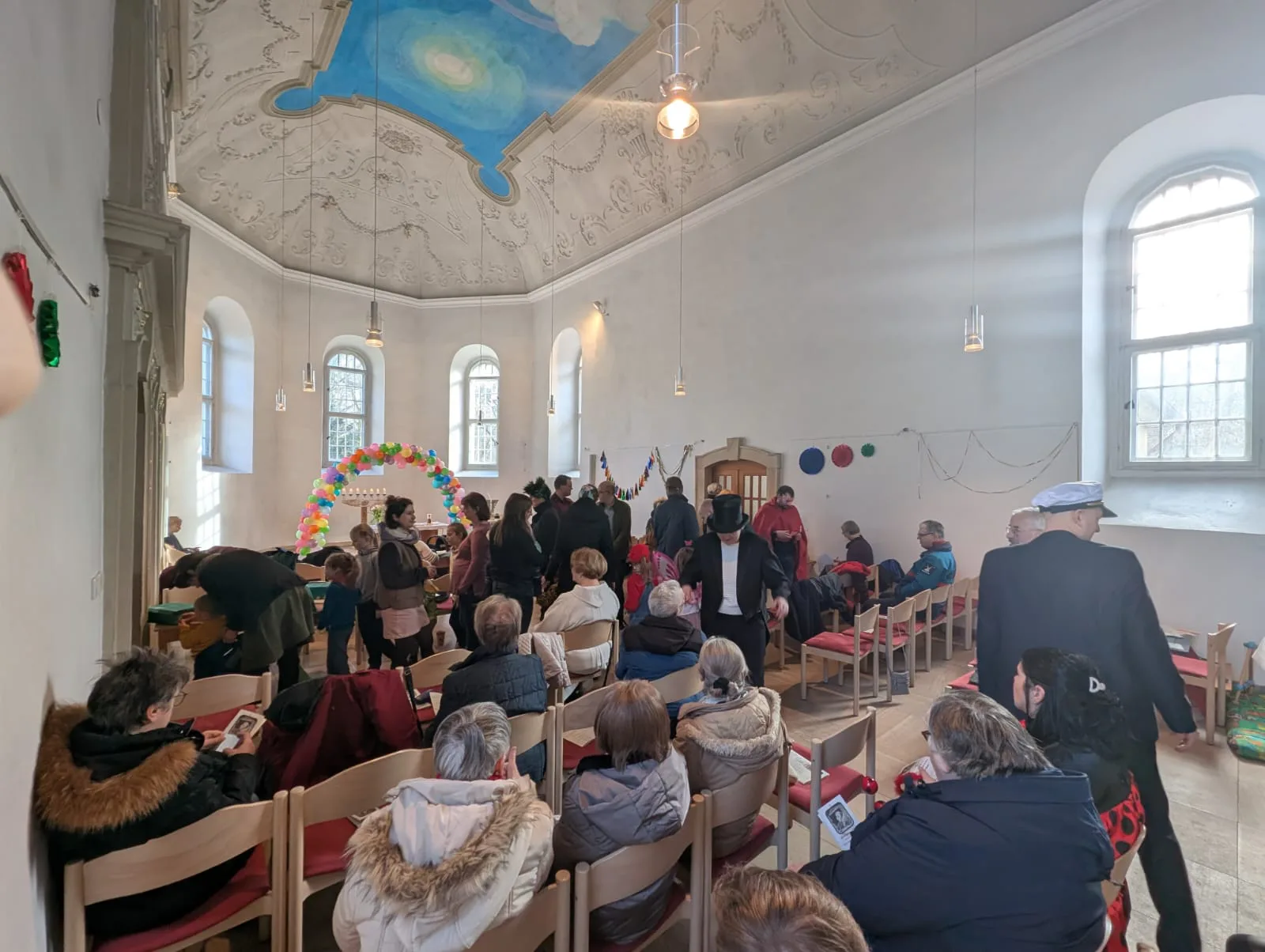 Der Faschingsgottesdienst mit bunten Luftballons und vielen Menschen. Einige sind verkleidet.