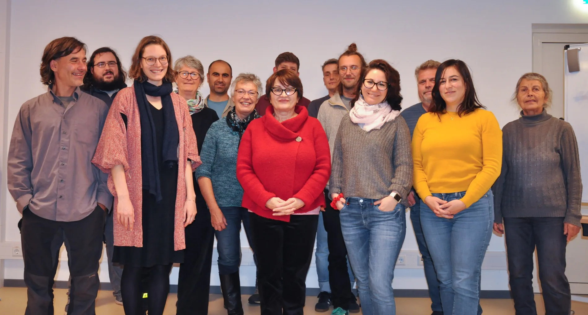 Es sind 14 Personen unterschiedlichem Alter auf dem Gruppenbild zu sehen, die in die Kamera lächeln.