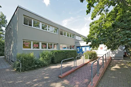 Es ist der Eingang der Stadtteilbibliothek West zu sehen mit Fahrradständern davor.