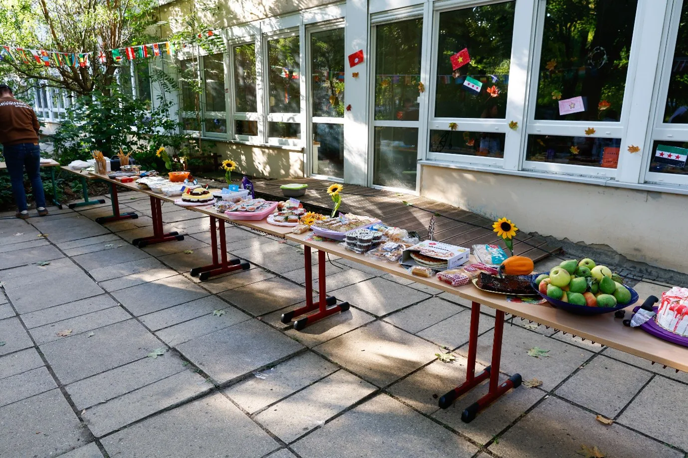 Vor dem Hort ist eine Reihe an Tischen zu sehen, auf denen ein großes Buffet steht.