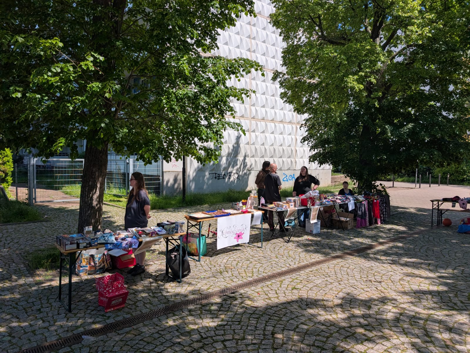 Mehrere Stände mit Essen und ein paar Menschen vor dem Quartiersladem beim Nachbarschaftsfrühstück